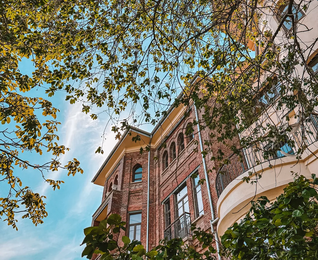 Historisches Backsteinwohnhaus wird von grünen Ästen und Baumkronen gerahmt